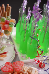 Bottles of drink with straw and sweets on dark background