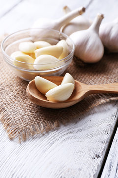 Fresh sliced garlic in glass bowl on wooden background