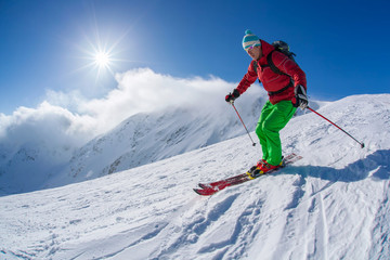 Skier skiing downhill in high mountains against sunset