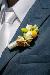 Close up a buttonhole of the groom from beige roses and cinnamon
