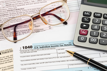 Tax form with pen, calculator, and glasses taxation concept