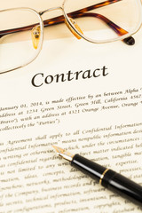 Business contract document on cream color paper with pen and gla