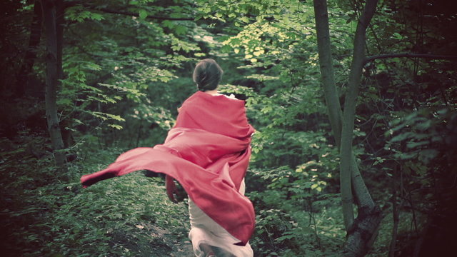 Woman in red cape running in the forest