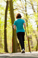 Nordic walking. Woman hiking in the forest park.