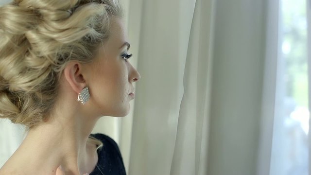 Beautiful blonde woman looking at window waiting for someone
