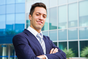 Smiling young businessman standing outside a building