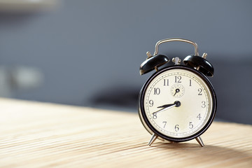 Retro alarm clock on desk front grey wall background