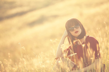 Beautiful brunette women with suitcase on autumn meadow in sunse