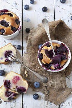 two clafoutis with blueberries and cherries on rustic background