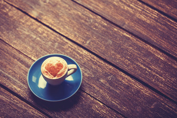 Cup of coffee with shape heart on wooden table.