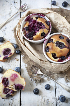 two clafoutis with blueberries and cherries on rustic background