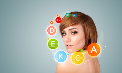 Pretty young girl with colorful vitamin icons and symbols