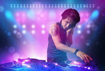 Obraz na płótnie Canvas Disc jockey mixing music on turntables on stage with lights and
