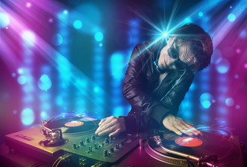 Obraz premium Dj mixing music in a club with blue and purple lights