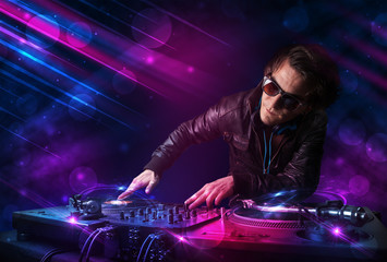 Young DJ playing on turntables with color light effects