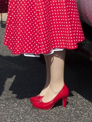 Rotes Kleid mit weißen Pünktchen, Petticoat und rote Pumps im Sommer bei Sonnenschein beim...