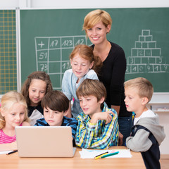 lächelnde lehrerin mit schulkindern am laptop