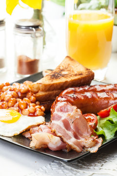 Full English breakfast with bacon, sausage, egg, beans and juice