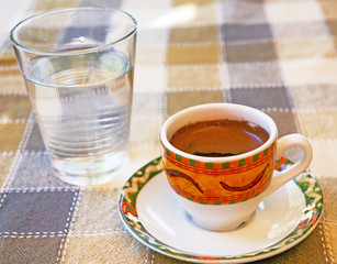 Strong Cypriot coffee with water water in a glass