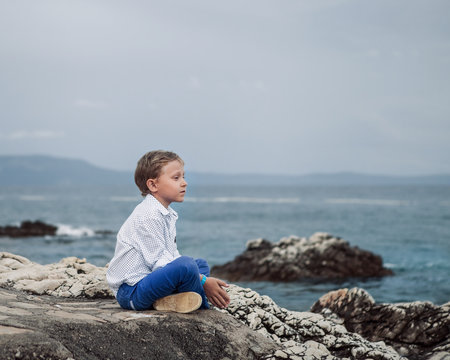Little boy sitting calm on the solitade sea beach