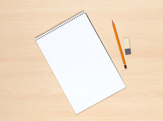 Blank notepad, pencil and eraser on the wooden table