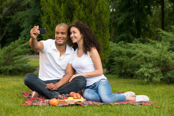 Happy romantic couple taking pictures on picnic