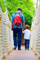 father and son travelling by suspension bridge
