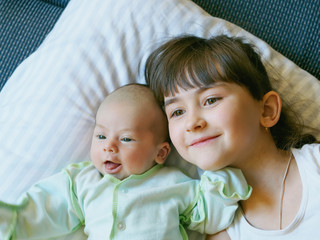 Caucasian child sister and baby brother lying together at home