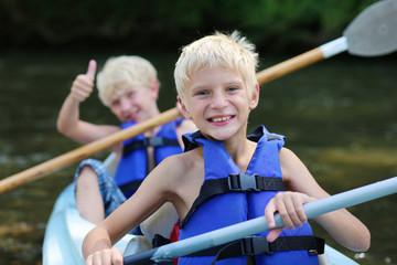 Two happy boys enjoying kayak on the river