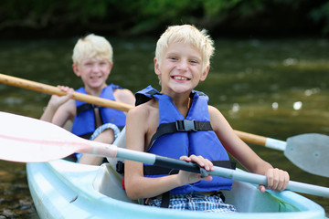 Two happy boys enjoying kayak on the river