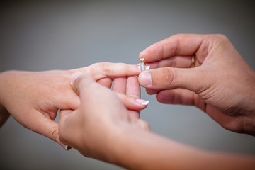Man placing a diamond engagement ring on the finger of his fianc