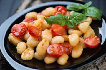 Roasted gnocchi with cherry tomatoes and green basil, close-up