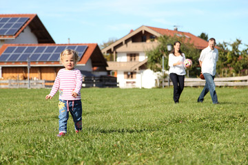 Familie mit kleiner Tochter rennt und spielt Ball