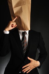 紙袋で顔を隠したスーツのビジネスマンが考えている様子