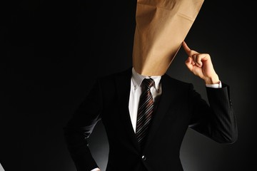 紙袋で顔を隠したスーツのビジネスマンが考えている様子