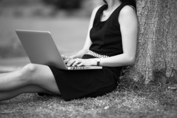 Naklejka premium Beautiful young woman using laptop in park