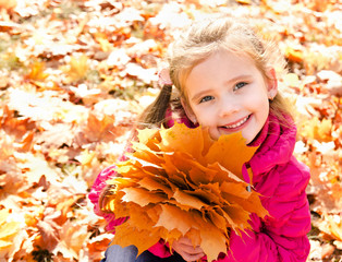 Naklejka na ściany i meble Autumn portrait of cute smiling little girl with maple leaves