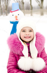 Portrait of smiling little girl with snowman