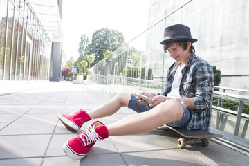 Teenager sitting on skateboard with tablet pc