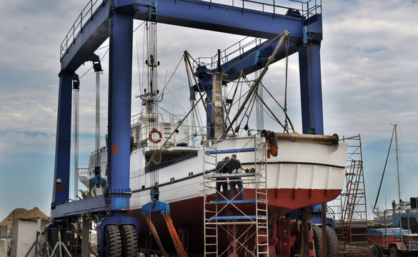 Operai riparano peschereccio in cantiere navale