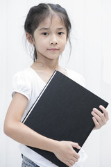 Obraz premium Asian little girl hold big black textbook.