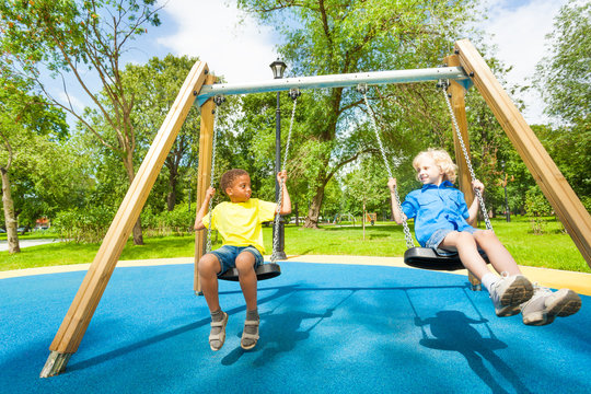 Kids on swings staring at each other and sit