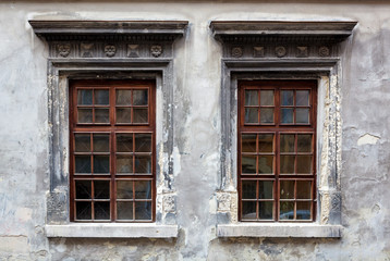 Two windows on an old gray stucco wall.