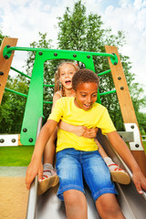Boy start to slide on chute and girl sit behind