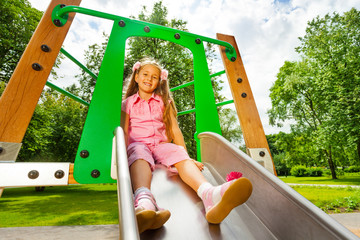 Pretty small girl on chute sitting and smiling