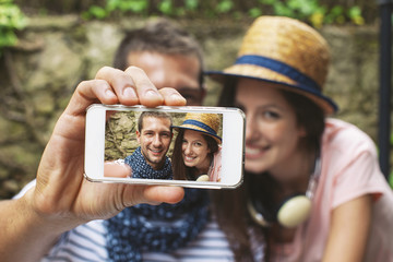 Young couple taking selfie with smart phone camera in outdoors.