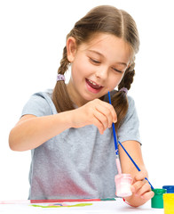 Little girl is painting with gouache