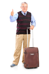 Mature man holding a suitcase and giving thumb up