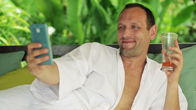 Man taking photo with smartphone, relaxing on gazebo bed 