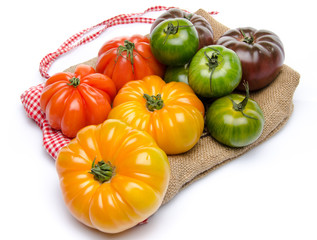 Fototapeta na wymiar Green, yellow, orange and purple tomatoes on a burlap